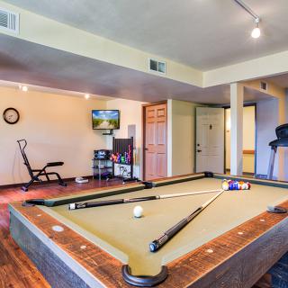 A well-equipped game room featuring a pool table, exercise equipment, and a television.