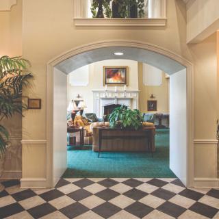 A cozy lobby featuring an archway entrance with a seating area and fireplace.