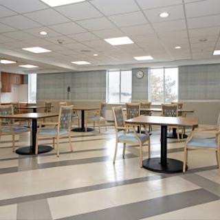 A spacious and modern dining area featuring wooden tables and chairs, illuminated by natural light from large windows.