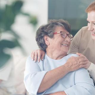 A warm moment between a caregiver and an elderly woman, filled with smiles and affection.