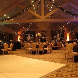 An elegantly decorated banquet hall set up for an event, featuring tables, chairs, and festive lighting.