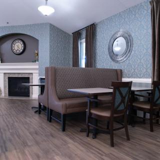A cozy dining area with a fireplace, featuring a booth and chairs for seating.