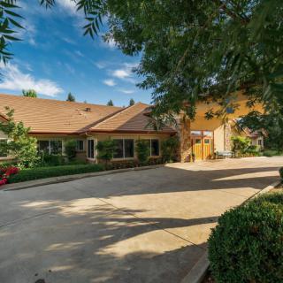 A spacious house with a wide driveway surrounded by lush landscaping on a sunny day.