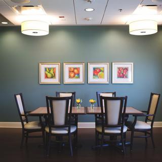 A modern dining room with a set table, contemporary artwork, and stylish overhead lighting.