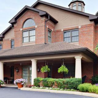 A brick residential building with a covered entrance and hanging plants.