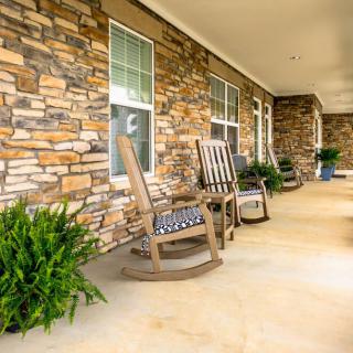 A cozy front porch with rocking chairs and a stone wall.