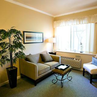 A cozy living room with a sofa, chair, and coffee table near a large window.