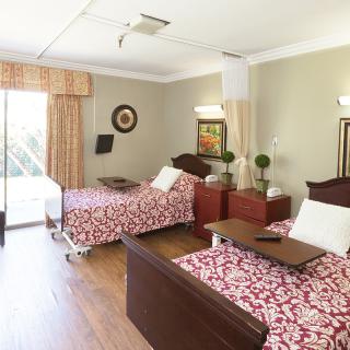 A shared hospital room with two neatly made beds and well-lit surroundings.
