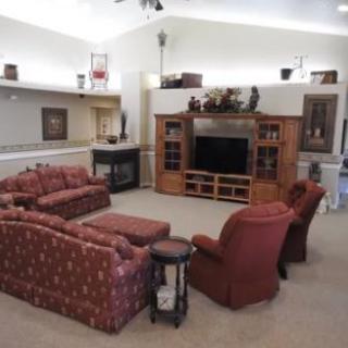 A cozy living room with a sofa set, television, and decorative shelves.