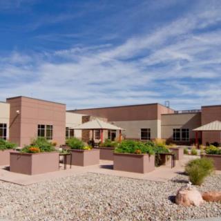 A modern building with desert landscaping under a clear blue sky.