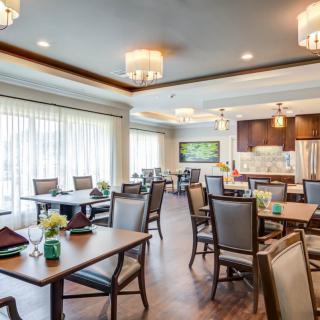 A spacious and elegantly designed dining room with neatly arranged tables and chairs, featuring modern lighting fixtures.