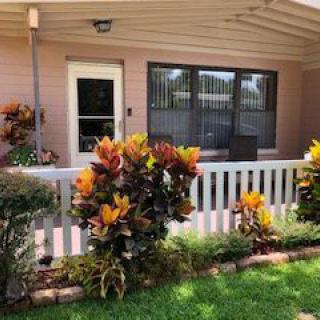 A cozy porch with vibrant plants and a small fence in a landscaped yard.