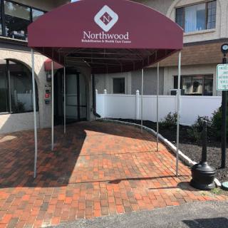 The entrance to Northwood hotel featuring a maroon awning and a brick-paved walkway.
