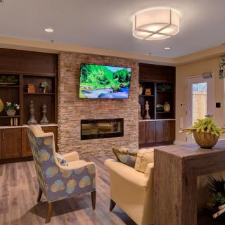 A modern living room with a fireplace and television, featuring cozy seating and stylish decor.