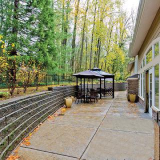A spacious patio with a gazebo surrounded by a lush forest in autumn.