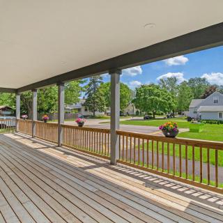 A spacious wooden porch overlooking a suburban neighborhood on a sunny day.