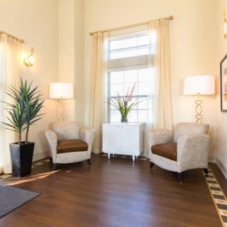 A bright and inviting living room corner featuring two comfortable chairs, soft lighting, and a decorative plant.