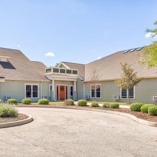 A large, single-story residential house with a circular driveway and minimal landscaping.
