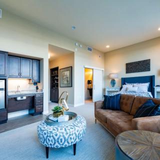 A modern open-concept living and bedroom area with a kitchenette, featuring stylish decor and comfortable furnishings.