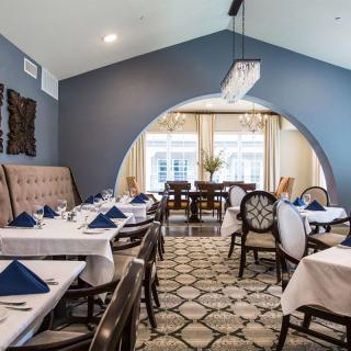 An elegantly decorated restaurant dining room with blue walls and neatly arranged tables.