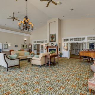 A spacious lounge area with elegant furniture, high ceilings, and a grand piano.