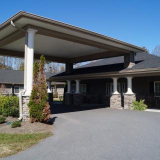 A building entrance with a covered driveway and decorative columns.