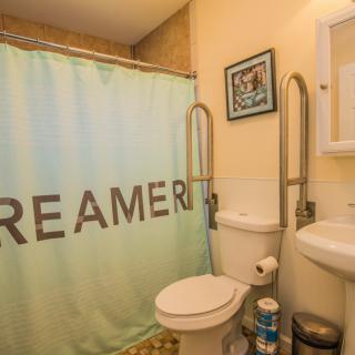 A compact bathroom featuring a toilet, sink, and a shower with a curtain displaying the word 'DREAMER'.