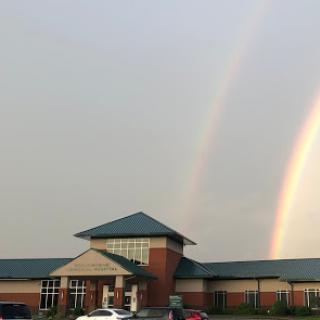 A beautiful view of a building with two rainbows in the sky.