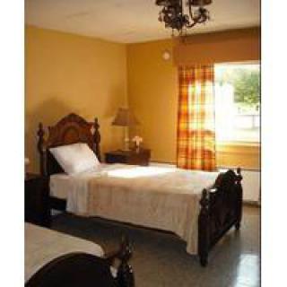 A cozy bedroom with a single bed, wooden furniture, and warm yellow walls.