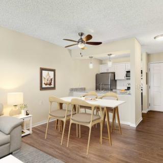 A modern apartment interior featuring a cozy living room and dining area connected to an open kitchen.