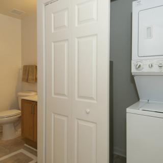 A view of a bathroom adjacent to a compact laundry area with a stacked washer and dryer.