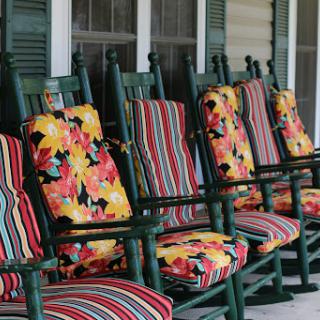 A row of inviting rocking chairs adorned with vibrant floral and striped cushions, perfect for a relaxing afternoon on the porch.