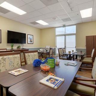 A well-lit meeting room with tables and chairs, featuring a television and various books and decor items on the tables.