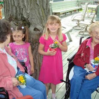 A joyful moment shared between children and elderly individuals, celebrating together with flowers.