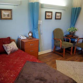 A cozy and well-decorated bedroom featuring a red bedspread, wooden furniture, and soft curtains.