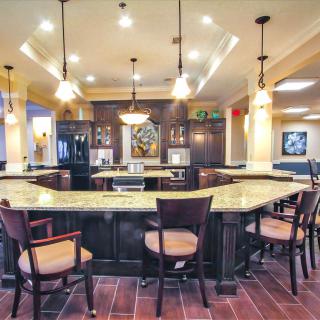 A modern kitchen with a bar setup, featuring elegant lighting and stylish furniture.