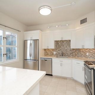 A modern kitchen with white cabinets, stainless steel appliances, and a decorative backsplash.
