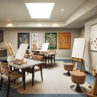 A well-lit art studio with easels and paintings on the walls.