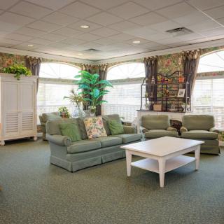A cozy living room with green sofas, a white coffee table, and large windows letting in natural light.