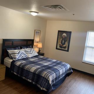 A neatly arranged bedroom with a bed, lamp, and window.