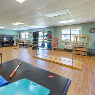 A spacious rehabilitation center room equipped with exercise tools and parallel bars for physical therapy.