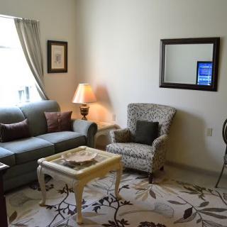 A cozy living room with a sofa, armchair, and coffee table complementing a soft lamp light.