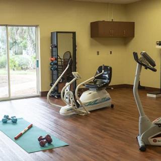 A home gym setup with exercise equipment including a stationary bike, a yoga mat, and dumbbells.