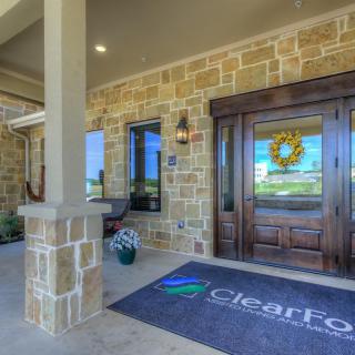 A welcoming entrance with a stone facade and decorative wreath, featuring a glass door and an outdoor seating area.