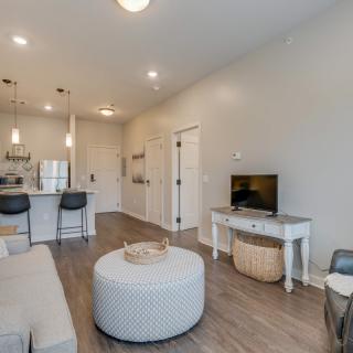 A modern and minimalist living room with an open floor plan, featuring a kitchen area, neutral colors, and stylish furniture.