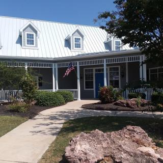 A charming house with a porch, surrounded by a garden and featuring an American flag.