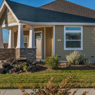 A single-story house with a porch and landscaped front yard on a sunny day.
