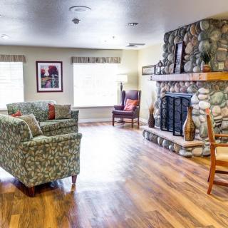 A cozy living room featuring a stone fireplace, comfortable seating, and wooden flooring.