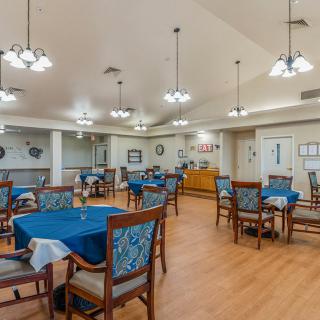 An empty dining room with several tables and chairs, featuring elegant lighting and decor.
