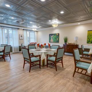 A well-decorated dining room with neatly arranged tables and chairs, complemented by elegant art pieces and ambient lighting.